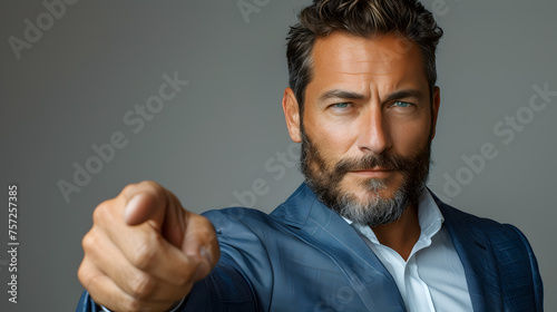 Confident businessman in a blue suit pointing at the camera. Corporate leadership and recruitment concept. Design for career advertisement, professional coaching, and corporate branding. Close-up