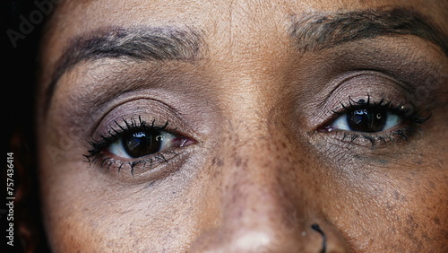One black hispanic middle-aged 50s woman macro close-up eyes looking at camera with solemn serious gaze, South American person of African descent