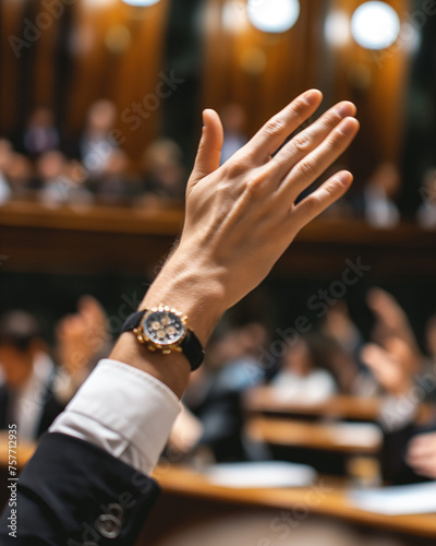 News journalism: A parliamentarian's hand raised in voting within the parliament, capturing the essence of democratic decision-making in action.