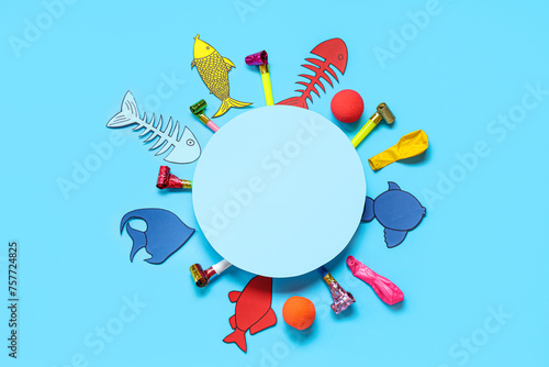 Blank card with paper fishes and party whistles on blue background. April Fools Day celebration