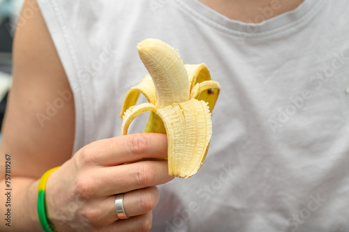Banan trzymany w dloni, mężczyzna je banana