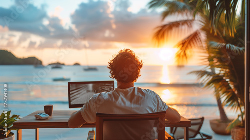 An office worker sits at his desk with his laptop and imagines watching the sunset on an exotic beach. Dream of going on vacation to the sea