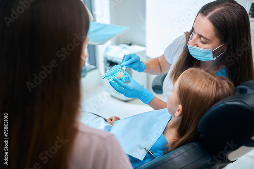 Doctor hygienist teaches a girl to brush her teeth correctly