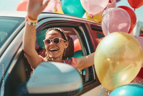 A joyful young woman waving from the window of a car, adorned with colorful balloons, setting off for a fun-filled holiday journey