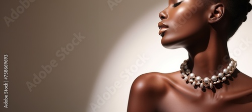 Beautiful ebony woman with pearl necklace on a beige background with copy space.