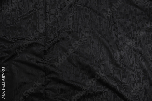 Texture of black taffeta (silk) fabric with black polka-dot pattern, top view. Background, texture of draped dressy fabric with shining black polka-dot pattern.