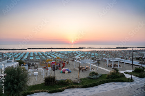 Beautiful sunrise on Rimini beach with umbrellas