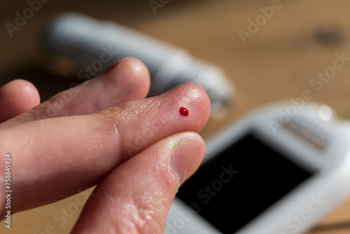 Woman pricking her finger to check blood glucose level with glucometer, test blood glucose for diabetes