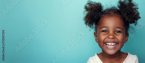 One smiling laughing youth 5 yr old girl African American pigtail curls hair portrait isolated blue empty indoor background child dental oral teeth childcare education wellness kid concept copyspace 