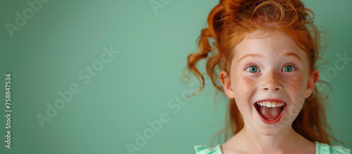 One silly shocked happy young 7 yr old girl portrait red ginger curly hair mouth open surprised excited funny healthcare education wellness campaign isolated on plain mint green background copyspace 