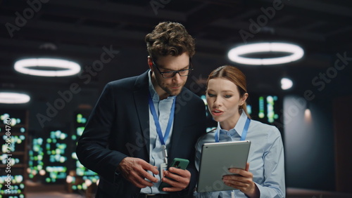 IT engineers working tablet in night data center closeup. Colleagues discussing