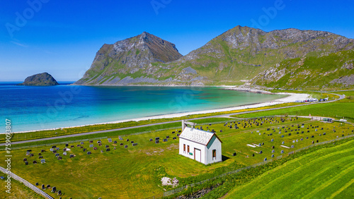 Beautiful norwegian wooden chapel with idyllic cemetery at the Haukland Beach with tropical clear water of the Atlantic Ocean. Haukland, Lofoten Islands, Norway.