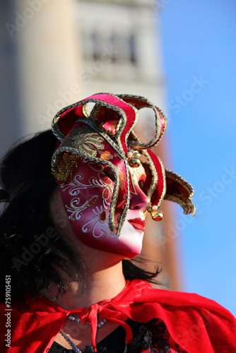 masked woman in a jester costume at Venice Carniva, with St. Marks Campanile