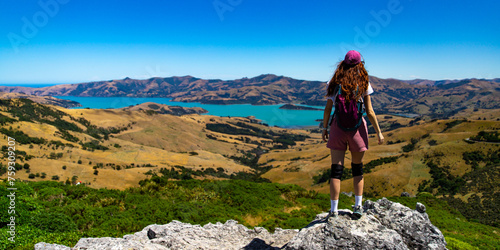 hiker girl admires the panorama of akaroa harbour and banks peninsula from the otepatotu scenic reserve, canterbury, new zealand south island near christchurch