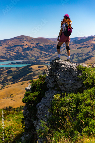 hiker girl admires the panorama of akaroa harbour and banks peninsula from the otepatotu scenic reserve, canterbury, new zealand south island near christchurch