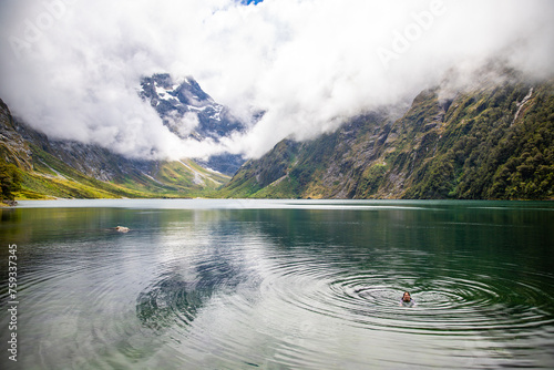 pretty girl in a swimsuit takes a bath in famous lake marian surrounded with mountains lake in fiordland national park near milford sound, new zealand south island