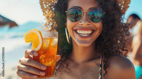 Beach woman drinking cold drink beverage having fun at beach party. Female babe in bikini enjoying Ice tea, coke or alcoholic drink smiling happy laughing looking at camera. Beautiful mixed race girl.