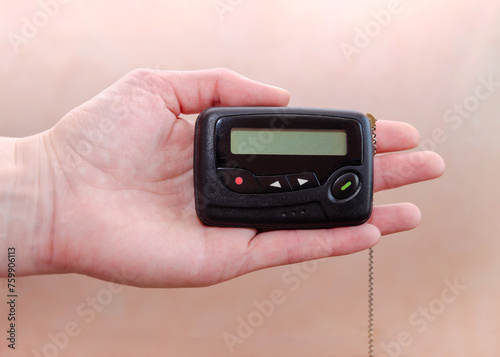 pager in close-up, an old retro communication device, in female hand on a beige background