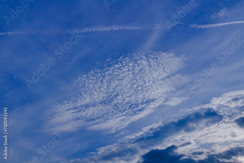Niebo lekko zachmurzone, częściowo pokryte białymi chmurami, zza których widać błękit nieboskłonu.