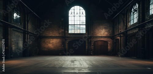 Spacious empty industrial loft with large windows and sunlight casting shadows on the wooden floor, evoking a moody atmosphere.