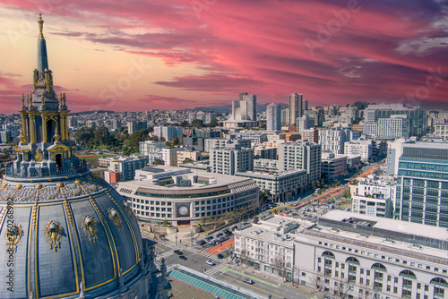 a stunning aerial shot of San Francisco City Hall surrounded by office buildings, apartments, lush green trees and cars on the street in San Francisco California USA