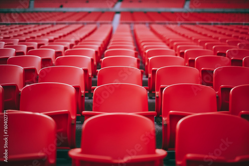 Football stadium with empty seats. Outstanding empty red plastic chair at soccer arena. Row of unoccupied bench at sports stadium. Reserved seating for football game concept. Outdoor audience chairs
