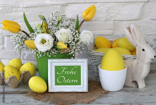 Ein Blumenstrauß mit Ostereiern und dem Text "Frohe Ostern" auf einer Karte.