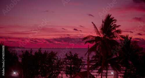 Banner pink sunset against the background of the ocean and palm trees. Amazing beautiful sunset on the islands.