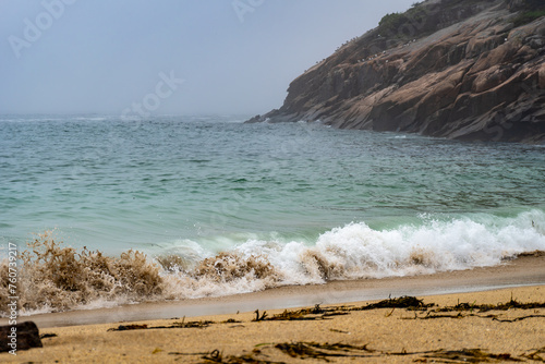 Crashing waves on Sand Beach in Acadia National Park, Maine. Surrounded by cliffs, this small stretch of coast is the largest sandy beach in Acadia. Rough surf on foggy, stormy day.