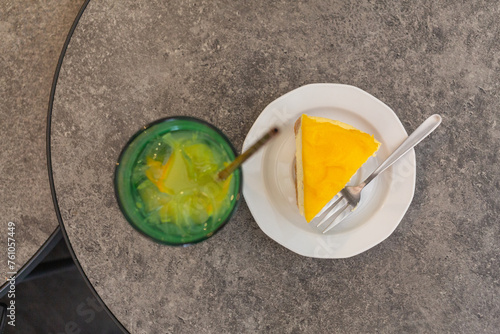an orange cheese cake on a white plate and a glass of juice on the table in cafe of lviv old city