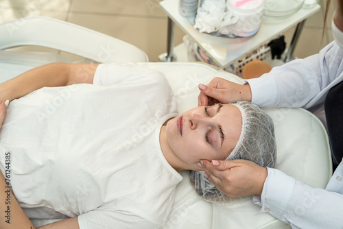 female cosmetologist doing relax massage woman face and neck with hands