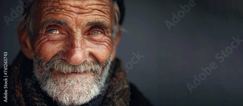 A man with a hat and beard is smiling. He looks happy and content. The hat is brown and has a pattern. photo of a smiling old man