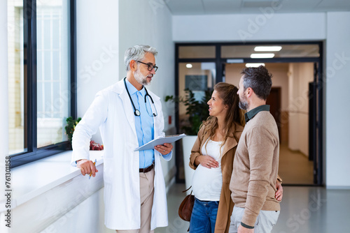 Pregnant woman and husband talking to obstetrician in hospital. Admitting woman in labor to maternity ward, planned cesarean section delivery.