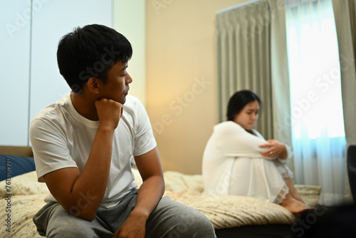 Unhappy married young couple sitting in bed, silence after conflict divorce quarrel