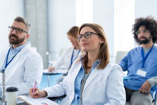 Group of doctors on conference, medical team sitting and listening speaker. Medical experts attending an education event, seminar in board room.
