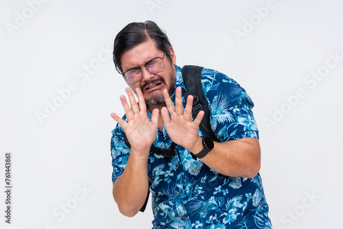 A cowardly middle-aged man in a Hawaiian shirt crying looking scared, pleading with hands up. Isolation on a white background conveys vulnerability. In trouble with the authorities in a foreign land.