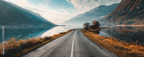Countryside roadway between mountains and calm lake