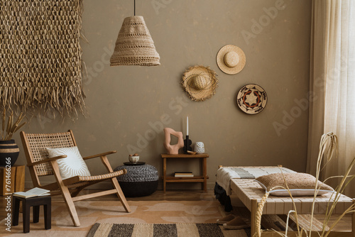 Interior design of ethno style living room with rattan furniture, daybed, pouf, hanging decoration on the wall, lamp and elegant personal accessories. Home decor. Template. 