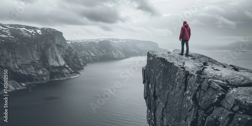 A person standing on a cliff overlooking a body of water. Suitable for travel and adventure concepts