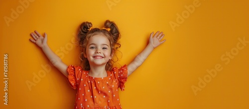 Photo of a chubby excited young woman wearing an orange dress. Plump lips, arms raised above head Empty space isolated yellow background