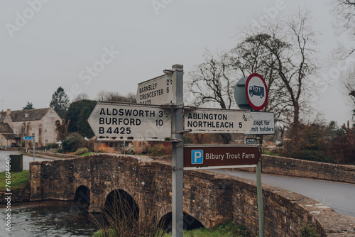 Directional signs to nearby towns with distances on a street in Bibury, UK.