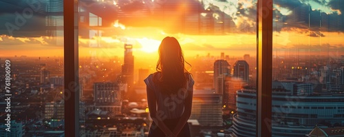 Woman contemplating cityscape through a window at sunset
