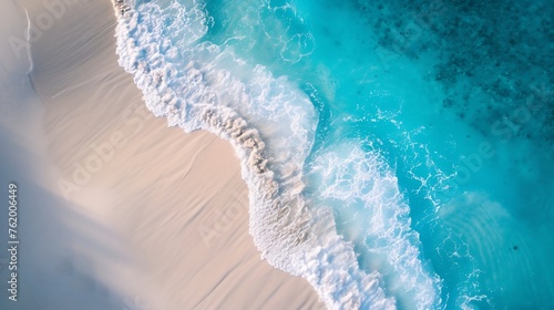 Stunning top view from a drone: beautiful beach waves of sea water hitting the sand on the shore. Atmospheric ocean landscape