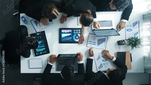 Top view of smart business people brainstorm marketing idea at meeting table while compare stock market investment data between laptop and tablet. Business team planning financial plan. Directorate.