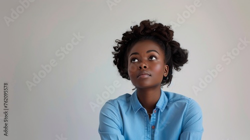 a lovely black woman in blue shirt is worried, she is looking in the distance as she was depressed