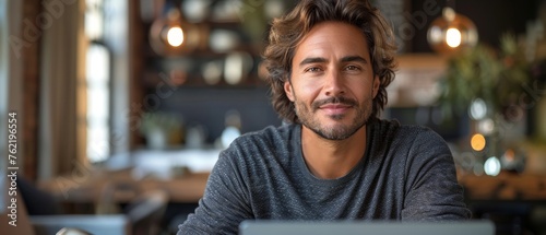 A happy young Latin businessman working at a laptop in a business office, looking away. Business man using a computer at his desk, thinking about corporate technology an AI solution. Copy space.