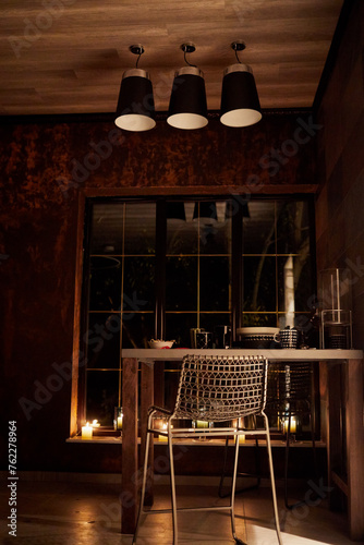 Table with crockery, burning candles near window in rest-room of bath-house in evening.