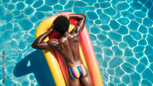 Gay man lying face down in swimming pool floating sunbathing in swimsuit with gay pride rainbow colors summer vacation at hotel. gay black man in summer sunbathing with athletic body