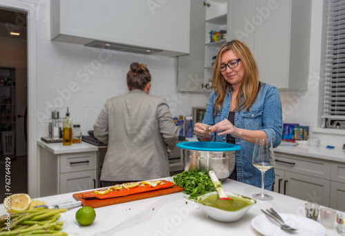 A Filipino woman pealing prawns in a big white luxury kitchen making salmon for friends for the dinner party she is throwing