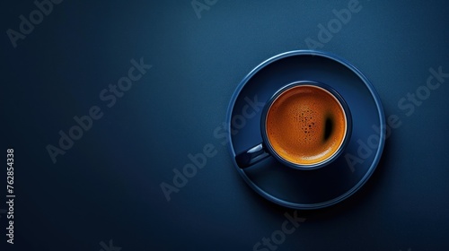 A cup of espresso coffee on a saucer background using dark blue color.